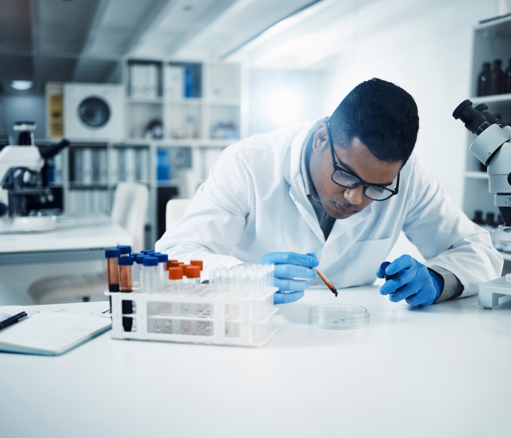 Scientist working in lab next to a microscope.